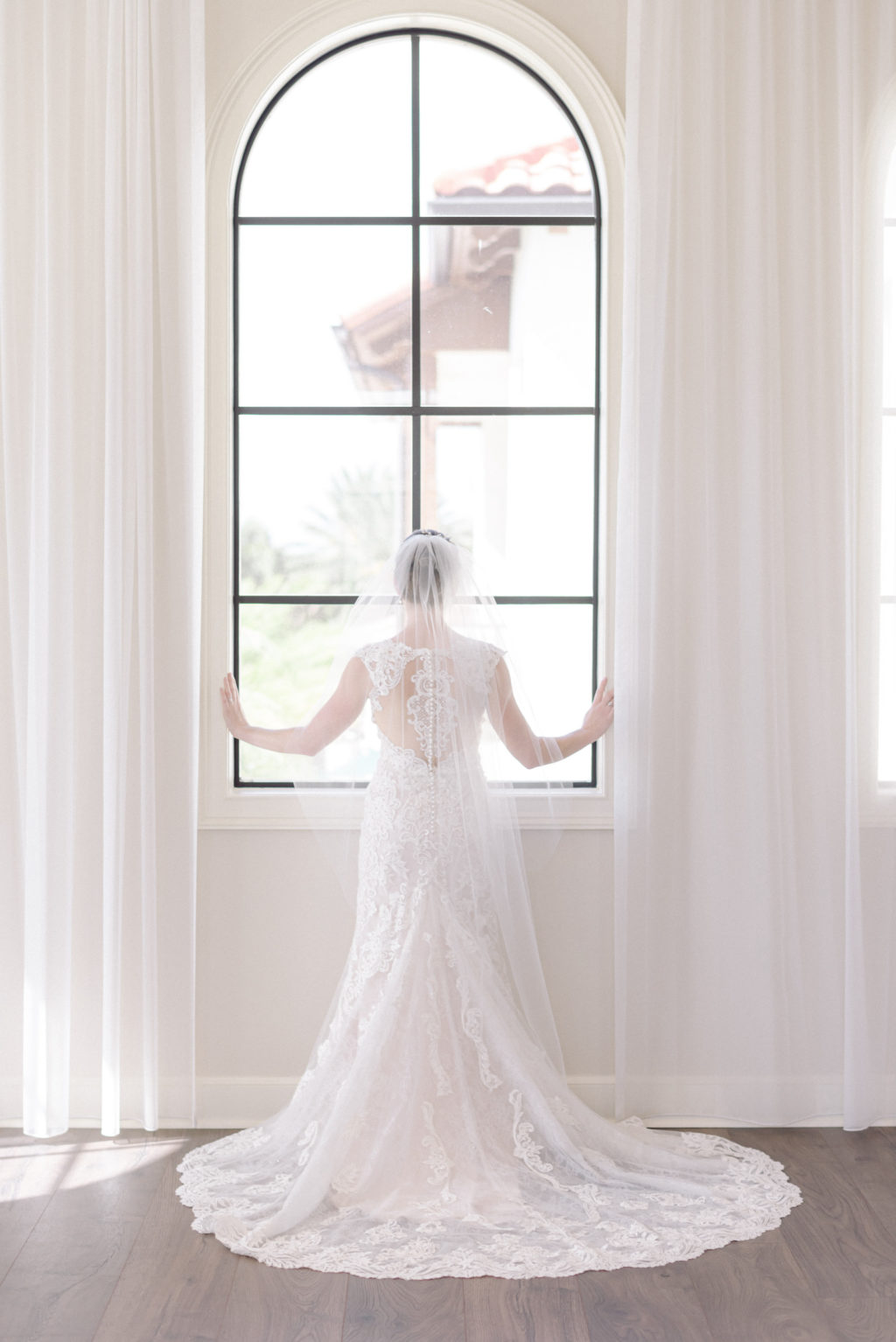 Tampa Bride Looking Out Window Wearing Lace and Illusion Wedding Dress