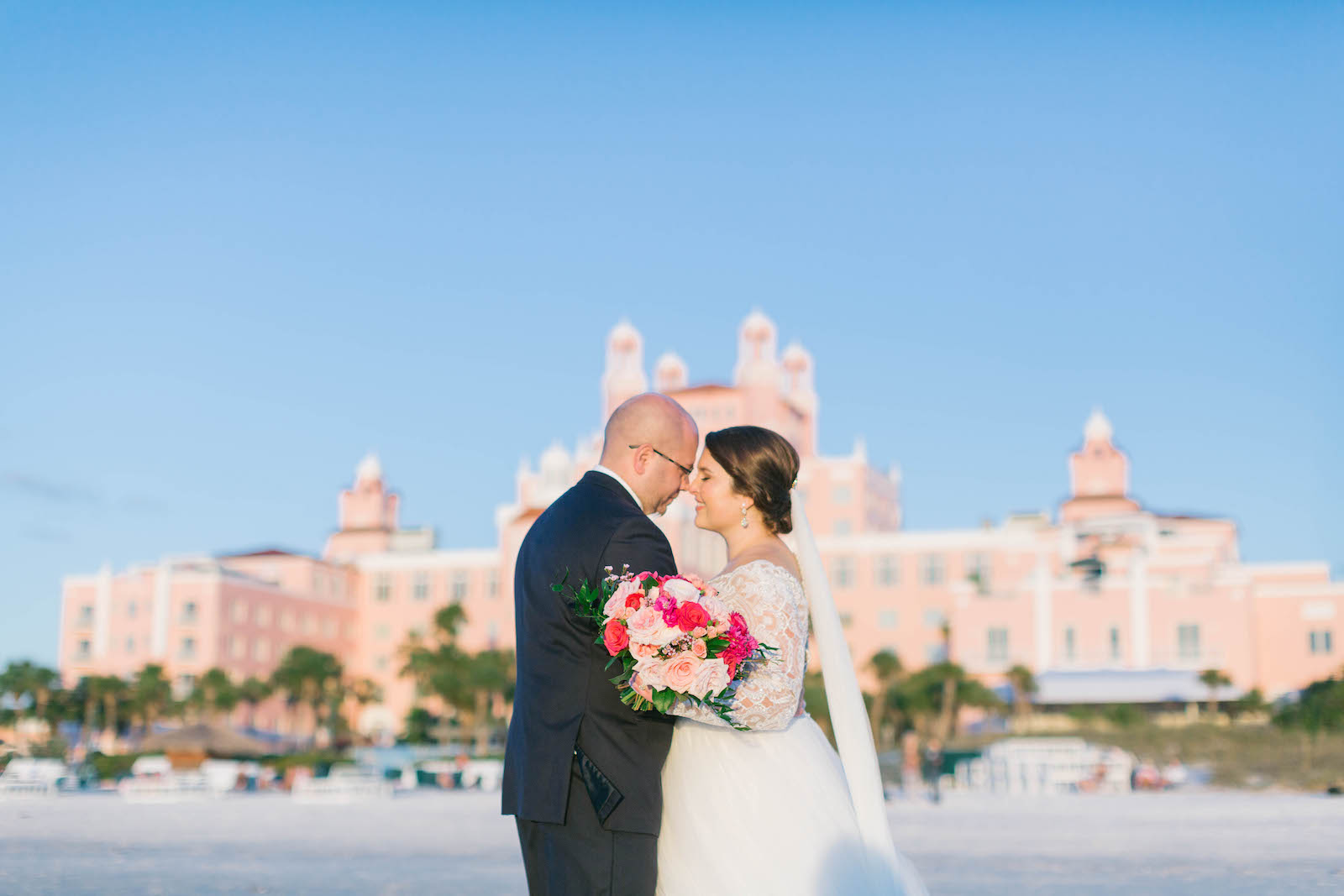 Florida Bride and Groom on Beach with Vibrant Pink Floral Bouquet | Historic Downtown St. Pete Wedding Venue The Don Cesar | Tampa Bay Wedding Florist Bruce Wayne Florals