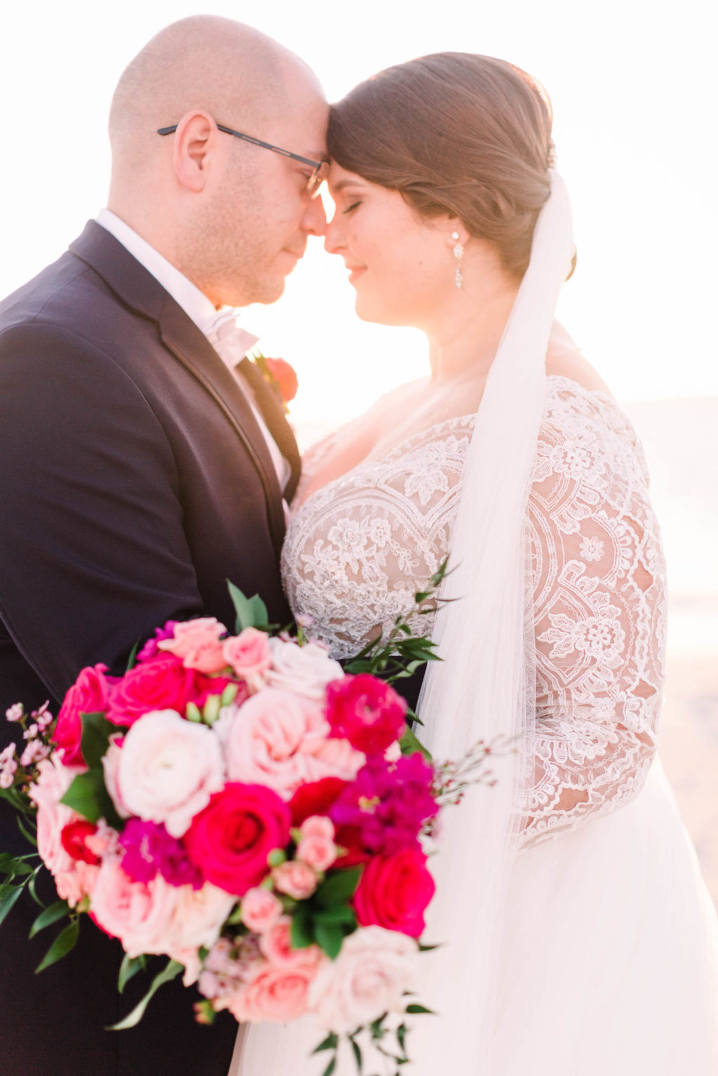 Romantic Sunset Bride and Groom Photo | Bride Wearing Lace and Illusion Long Sleeve Wedding Dress Holding Lush Vibrant Pink Floral Bouquet | Tampa Bay Wedding Florist Bruce Wayne Florals | Parties A'La Carte