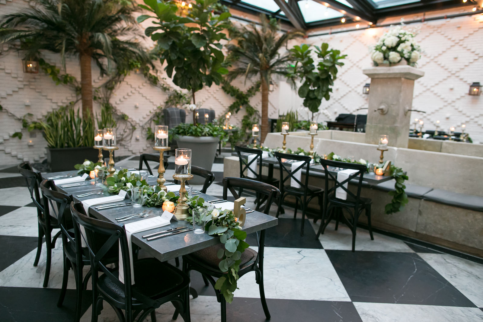 Tampa Wedding Reception at Oxford Exchange Downtown Tampa | Long Metal Banquet Tables with Black Cross Back Chairs and White Napkins | Wedding Centerpieces of Floating Pedestal Candles and Greenery Garland