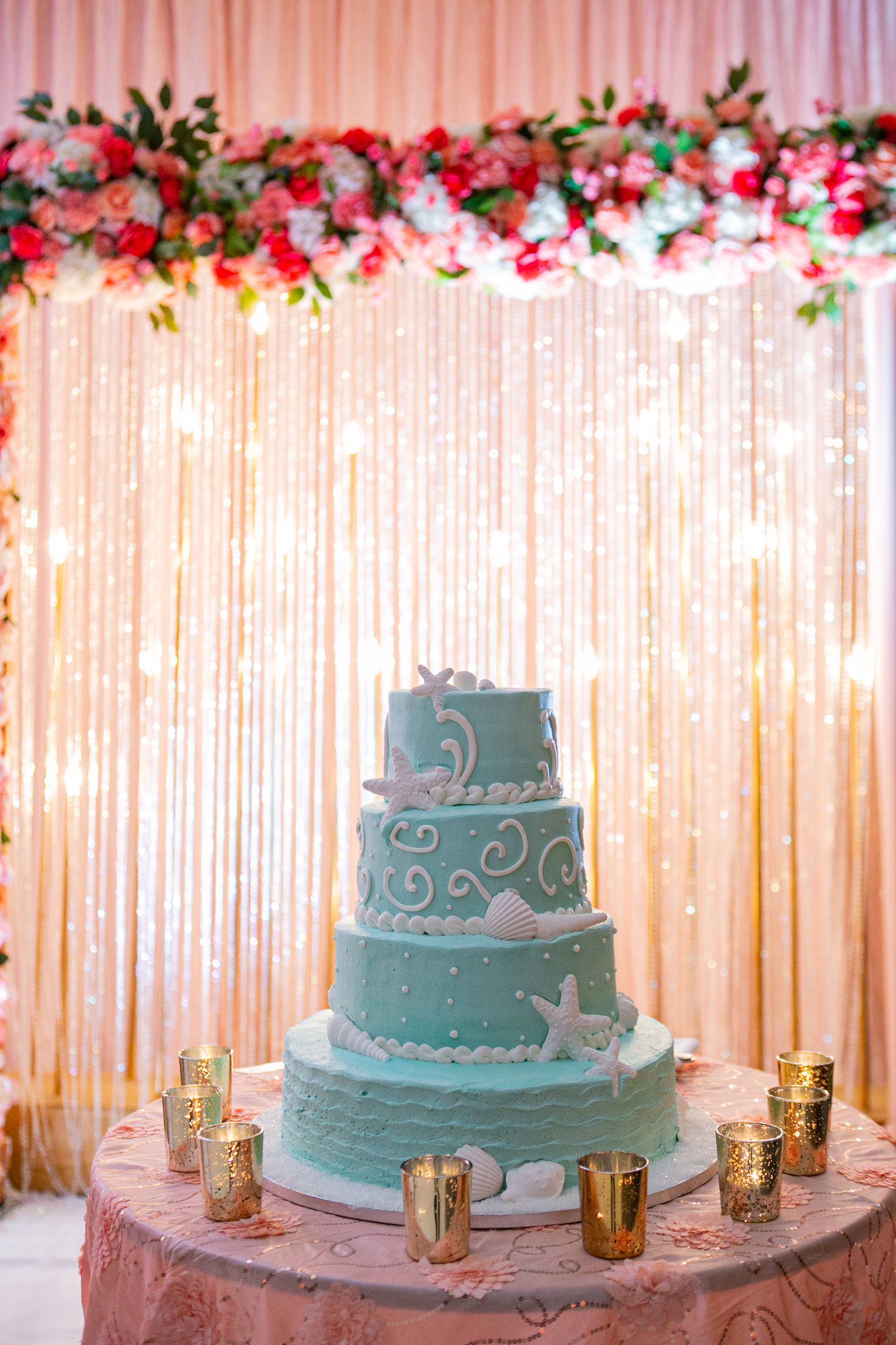 Tampa Clearwater Beach Indian Wedding Cake with Twinkle Light Curtain Wall | Four Tier Buttercream Turquoise Teal Aqua Beach Wedding Cake with Starfish and Sea Shells by Publix