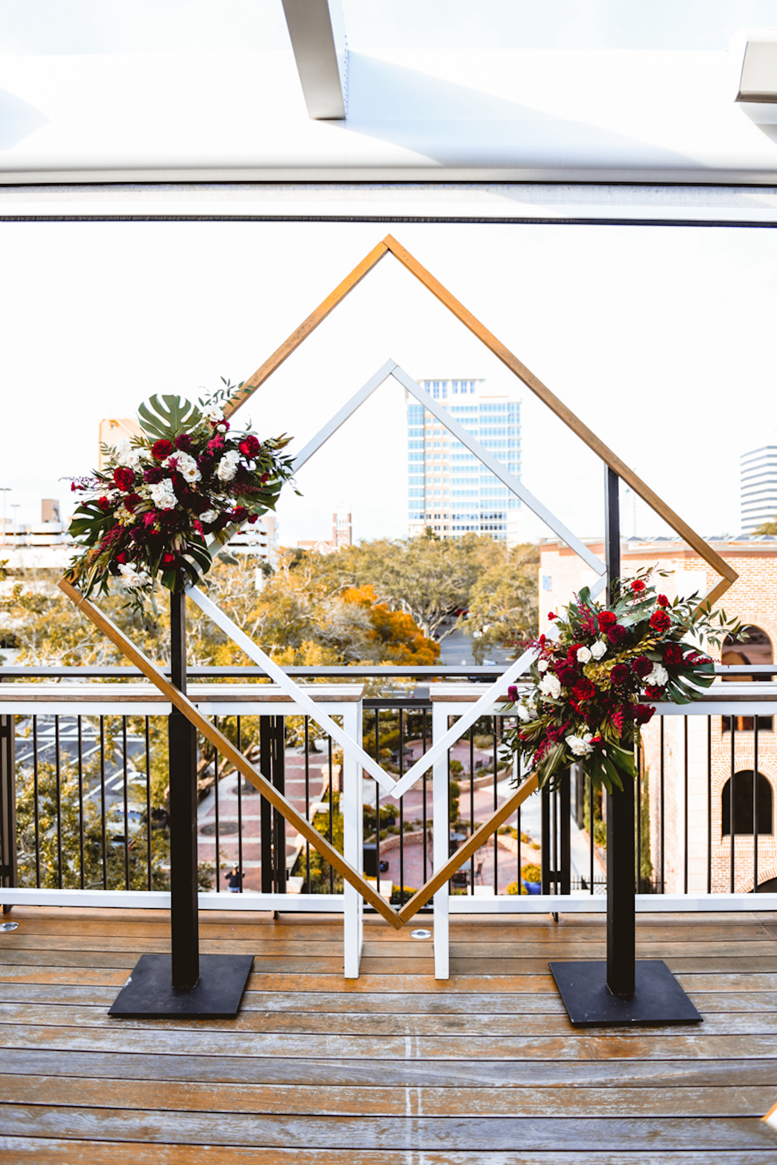Rooftop Geometric Gold Wedding Ceremony Arch Backdrop with Red and White Flowers and Monstera Palm Leave Arrangements | St. Petersburg Florida Wedding | St. Pete Wedding Venue Red Mesa Events | Tampa Wedding Planner Special Moments Event Planning