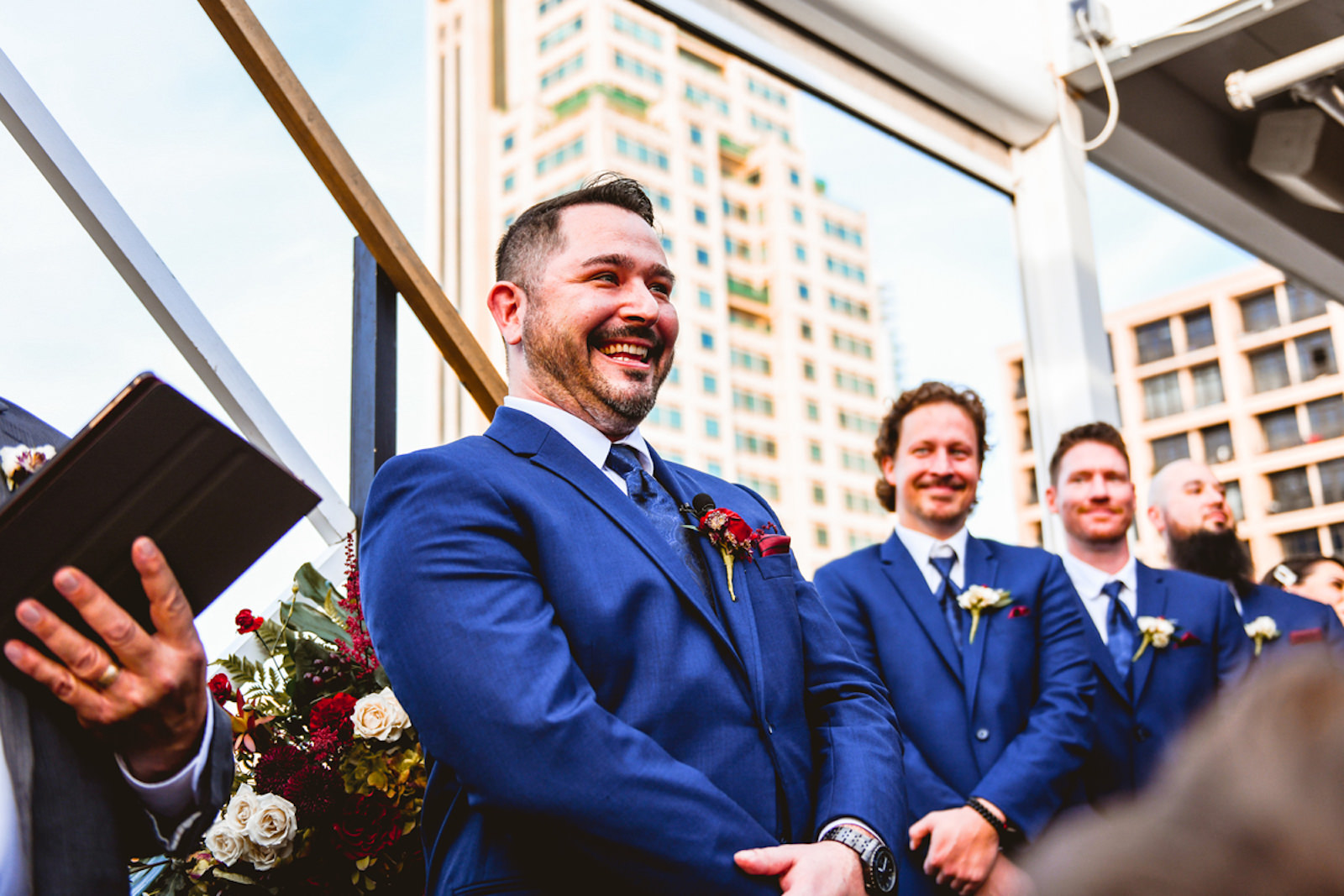 Tampa Groom in Blue Suit with Red Flower Boutonniere Happy Reaction to Seeing Bride During Rooftop Wedding Ceremony