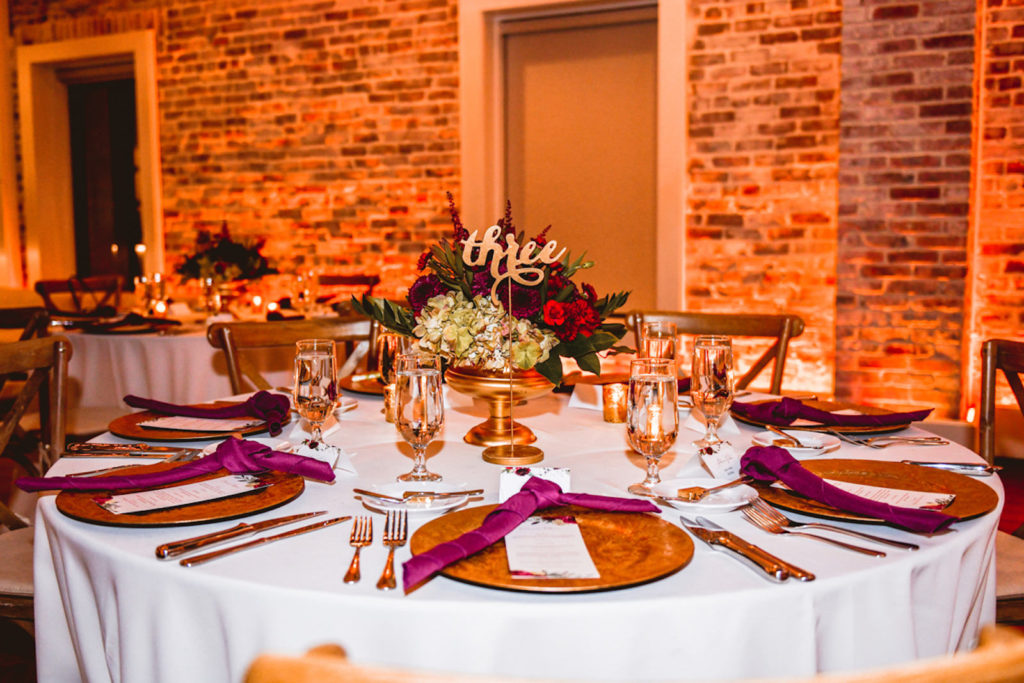 Botanical Inspired Wedding Reception Decor, Gold Chargers, Burgundy Red Linen Napkins, Low Red and Greenery Floral Centerpiece and Gold Laser Cut Table Number | Tampa Bay Wedding Planner Special Moments Event Planning | Downtown St. Pete Wedding Venue Red Mesa Events