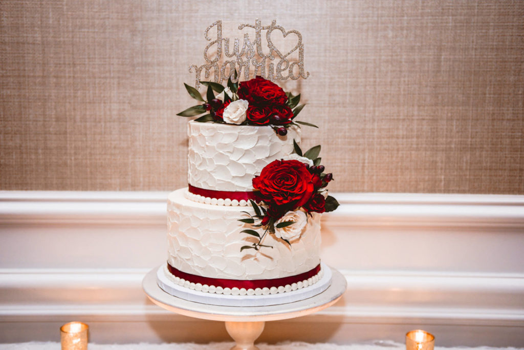 Two Tier White Textured Wedding Cake with Burgundy Ribbon and Red and Ivory Roses, Just Married Gold Glitter Cake Topper | Tampa Bay Wedding Cake Baker The Artistic Whisk