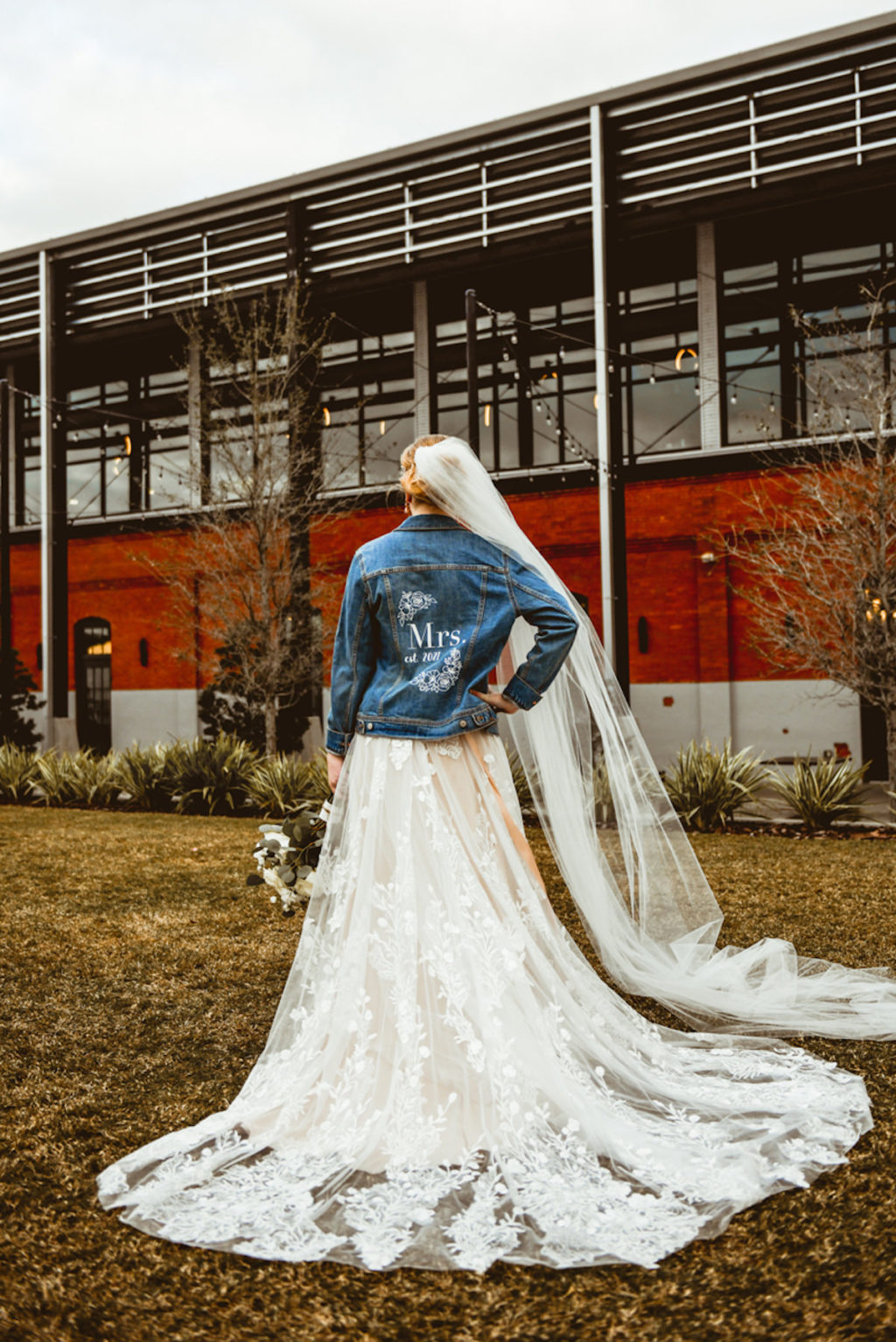 Boho Bride in Lace and Tulle Wedding Dress and Custom Denim Jacket with Full Length Veil | Tampa Industrial Wedding Venue Armature Works