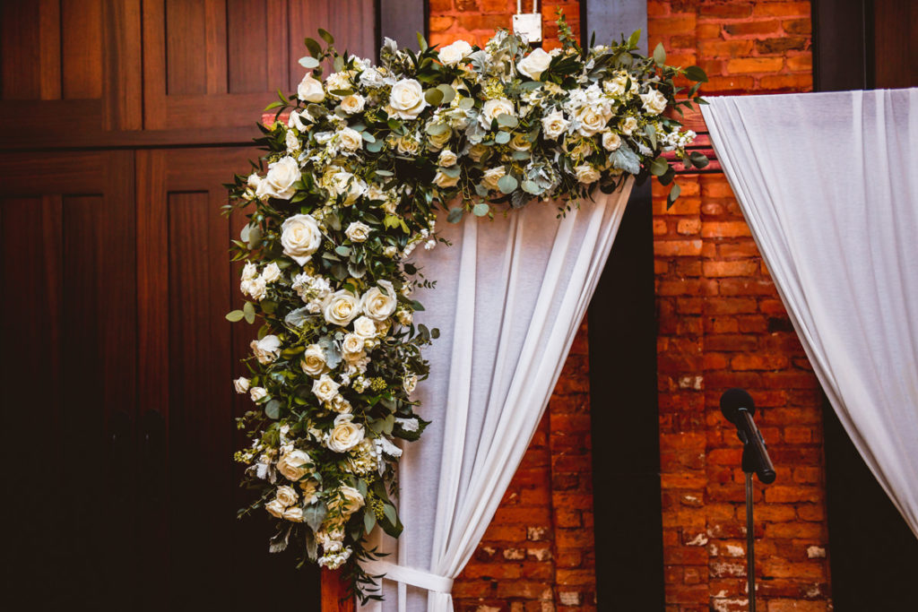 Industrial Wedding Reception Decor, Wooden Arch with White Linen Draping, Lush Greenery, Eucalyptus, Ivory Roses Floral Arrangement