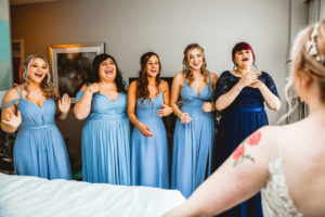 Bridesmaids in Mix and Match Dusty Blue Dresses Reaction to Seeing Bride in Wedding Dress | Tampa Bay Wedding Hair and Makeup Femme Akoi