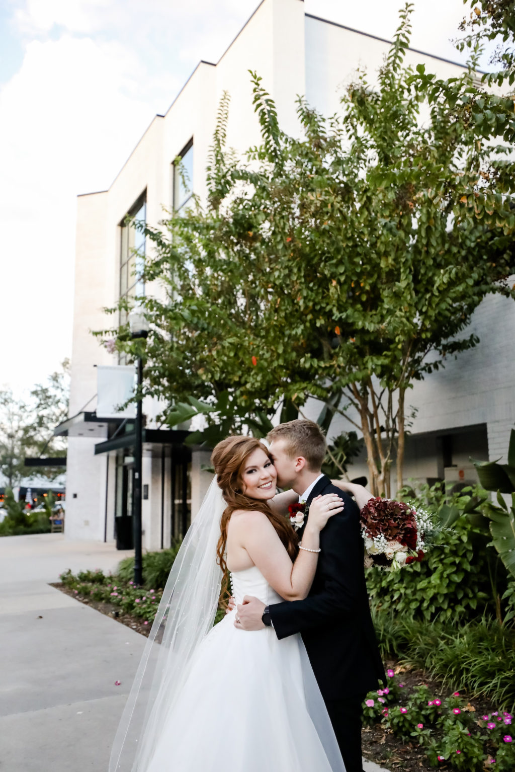 Bride and Groom Portrait at Tampa Wedding Venue Hyde House | Groom Wearing Classic Black Suit Tux | Bride Wearing Organza Sweetheart Neckline Sincerity Bridal Gown Wedding Dress with Long Pearl Studded Cathedral Veil | Bridal Wedding Bouquet with Burgundy and White Hydrangea, Red Carnations, White Roses, Baby's Breath and Greenery