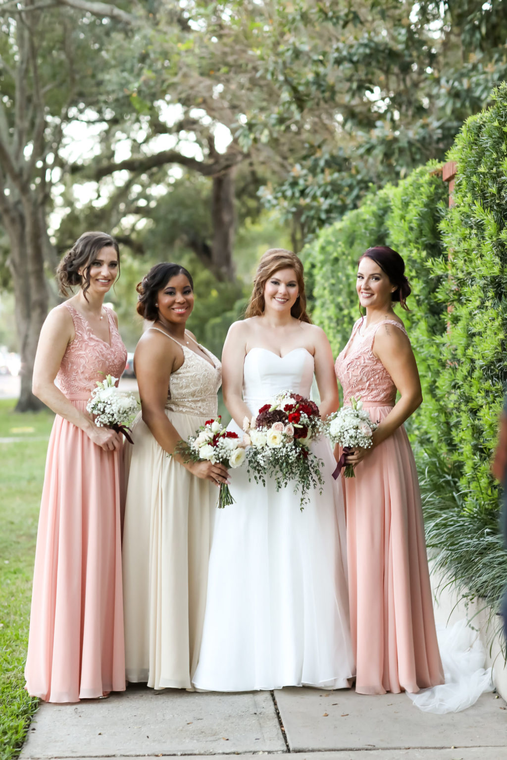 Bride and Bridesmaids Outdoor Portrait | Bride Wearing Organza Sweetheart Neckline Sincerity Bridal Gown Wedding Dress | Blush Pink Peach Champagne Long Chiffon and Lace Bridesmaid Dresses by Kennedy Blue | Bridal Wedding Bouquet with Burgundy and White Hydrangea, Red Carnations, White Roses, Baby's Breath and Greenery