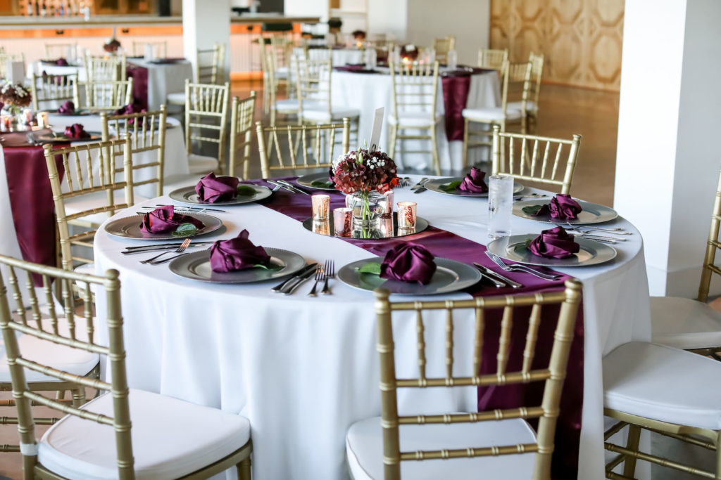 Tampa Wedding Reception at South Tampa Wedding Venue Hyde House | Round Reception Tables with White Linens and Burgundy Runners and Napkins with Gold Charger Plates and Gold Chiavari Chairs by A Chair Affair