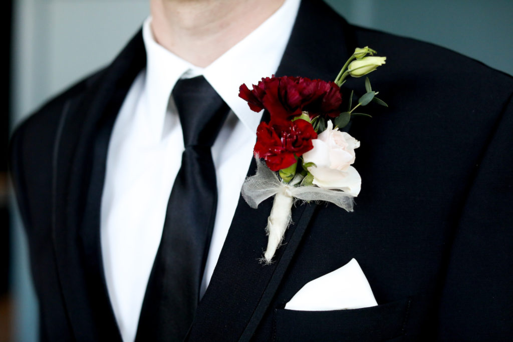 Burgundy Red and White Carnation and Spray Rose Groom Boutonniere | Groom Wearing Classic Black Suit Tux with Skinny Black Neck Tie