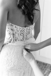 Black and white wedding Photography | Bride Getting Dressed with Sheer Illusion Lace Back Wedding Dress and Buttons | Dewitt for Love Photography