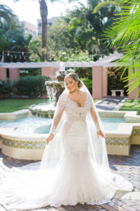 Tampa Bride Wearing Long Sleeve Lace and Illusion Plunging Neckline Wedding Dress in Front of Courtyard Water Fountain at St. Pete Vinoy Renaissance