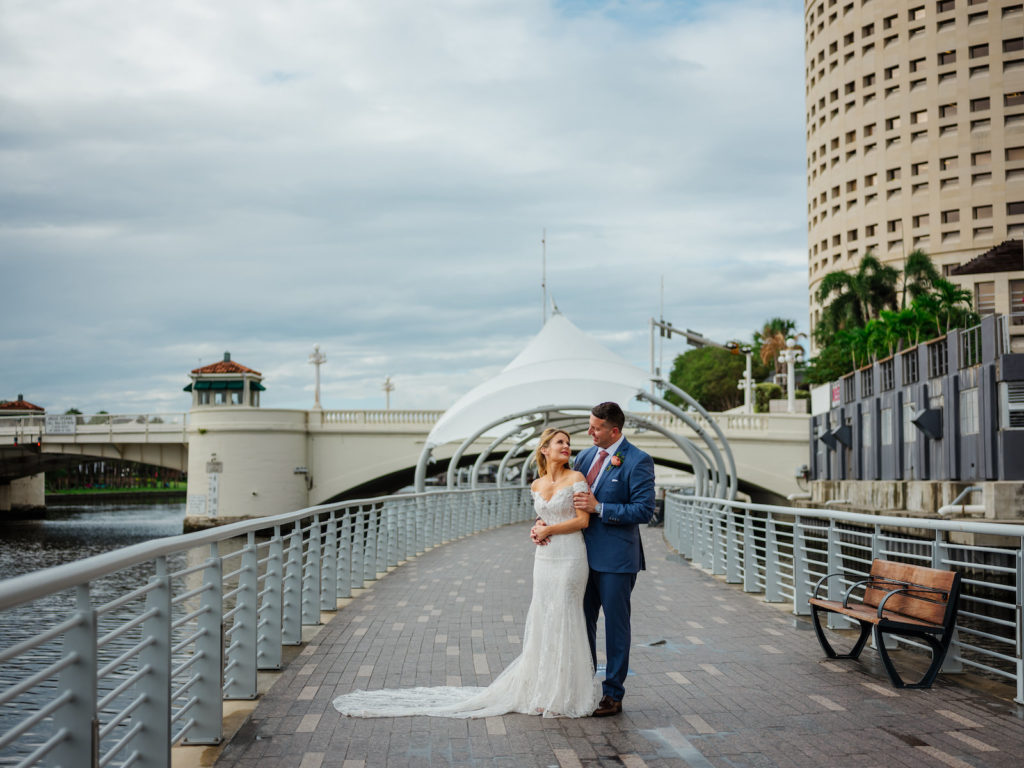 Tampa Bride in Romantic Lace Off the Shoulder Wedding Dress and Groom in Blue Suit on Waterway Dock
