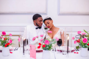 Bride and Groom Reception Portrait at Valentine Inspired Reception Feasting Table with Hurricane Glass Centerpieces with Pink and Red Florals by A Chair Affair | EventFull Weddings