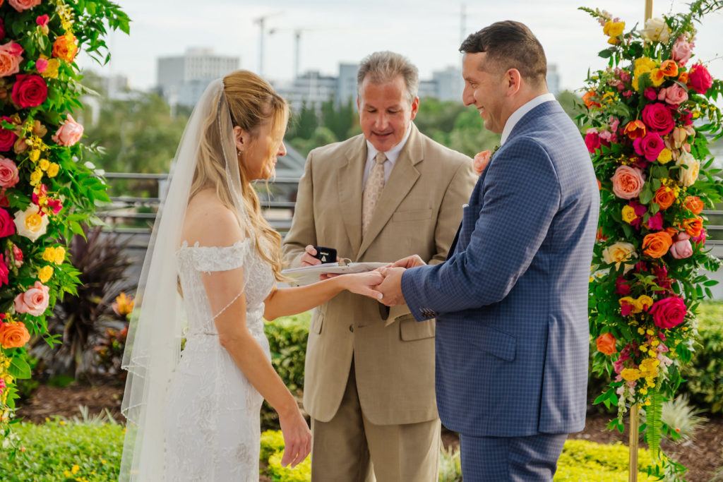 Bride and Groom Exchanging Wedding Vows During Elopement Ceremony, Gold Arch with Colorful Moroccan Inspired Florals, Red, Pink, Yellow and Orange Roses with Greenery | Tampa Bay Wedding Planner UNIQUE Weddings + Events