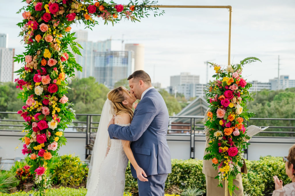 Bride and Groom Exchanging Wedding Vows During Elopement Ceremony, Gold Arch with Colorful Moroccan Inspired Florals, Red, Pink, Yellow and Orange Roses with Greenery | Tampa Bay Wedding Planner UNIQUE Weddings + Events