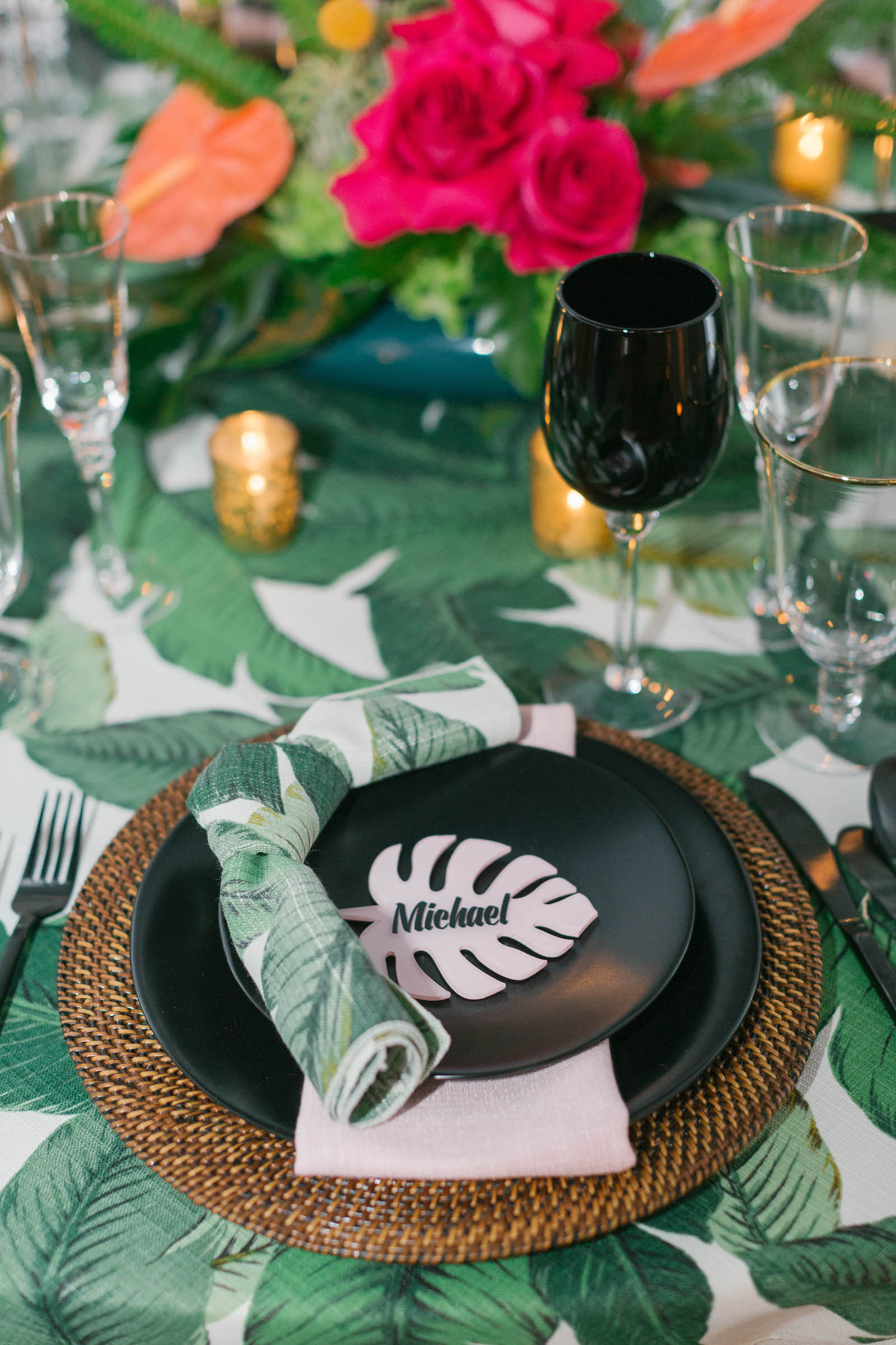 Palm Leave Linen with Wicker Charger, Black Place Setting, Palm Leaf Name Card,and Dishes, and Vibrant Pink and Orange Centerpiece | Tropical Destination Beach Wedding Inspiration | Bellwether Beach Resort Styled with Love by Marry Me Tampa Bay