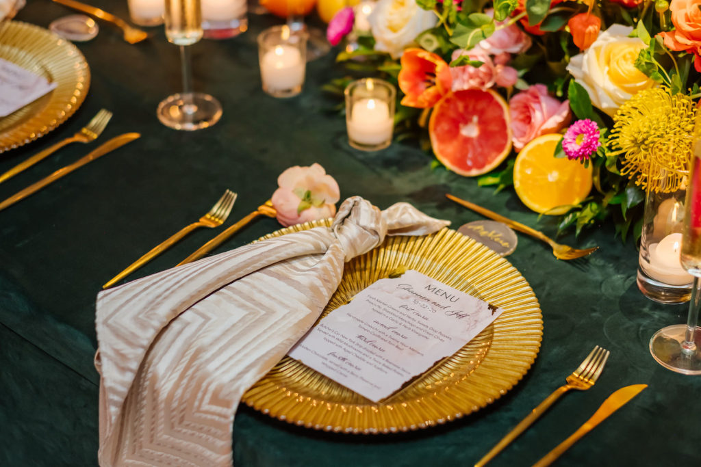 Moroccan Inspired Elopement Wedding Reception Decor, Orange Linen Drapery, Long Feasting Table with Dark Green Tablecloth, Colorful and Bright Orange, Yellow, Pink Flower Centerpieces, Grapefruit and Lemons Fruits, High Low Floating and Votive Candles, Gold Chargers and Flatware, Champagne Gold Linen Napkin, Custom Marbled Menu | Tampa Bay Wedding Planner UNIQUE Weddings + Events | Wedding Rentals Kate Ryan Event Rentals