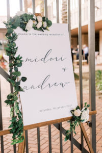Minimal Wedding Reception Decor, White Welcome Sign on Wooden Easel with Eucalyptus Greenery and White Roses Garland | Tampa Bay Wedding Photographer Kera Photography