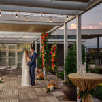 Florida Bride and Groom Outside Tampa Bay Wedding Venue Rooftop 220 at Armature Works, Gold Arch with Colorful Moroccan Inspired Lush Flower Arrangements, Yellow, Pink Fuschia, Orange Roses and Greenery | Wedding Planner UNIQUE Weddings + Events | Wedding Rentals Kate Ryan Event Rentals