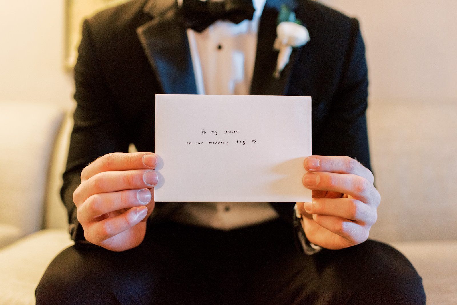 Groom Holding Note From Bride on Wedding Day Portrait in Tuxedo