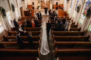 Traditional Timeless Bride Wearing Full Length Lace Trim Veil Walking Down Aisle During Church Ceremony