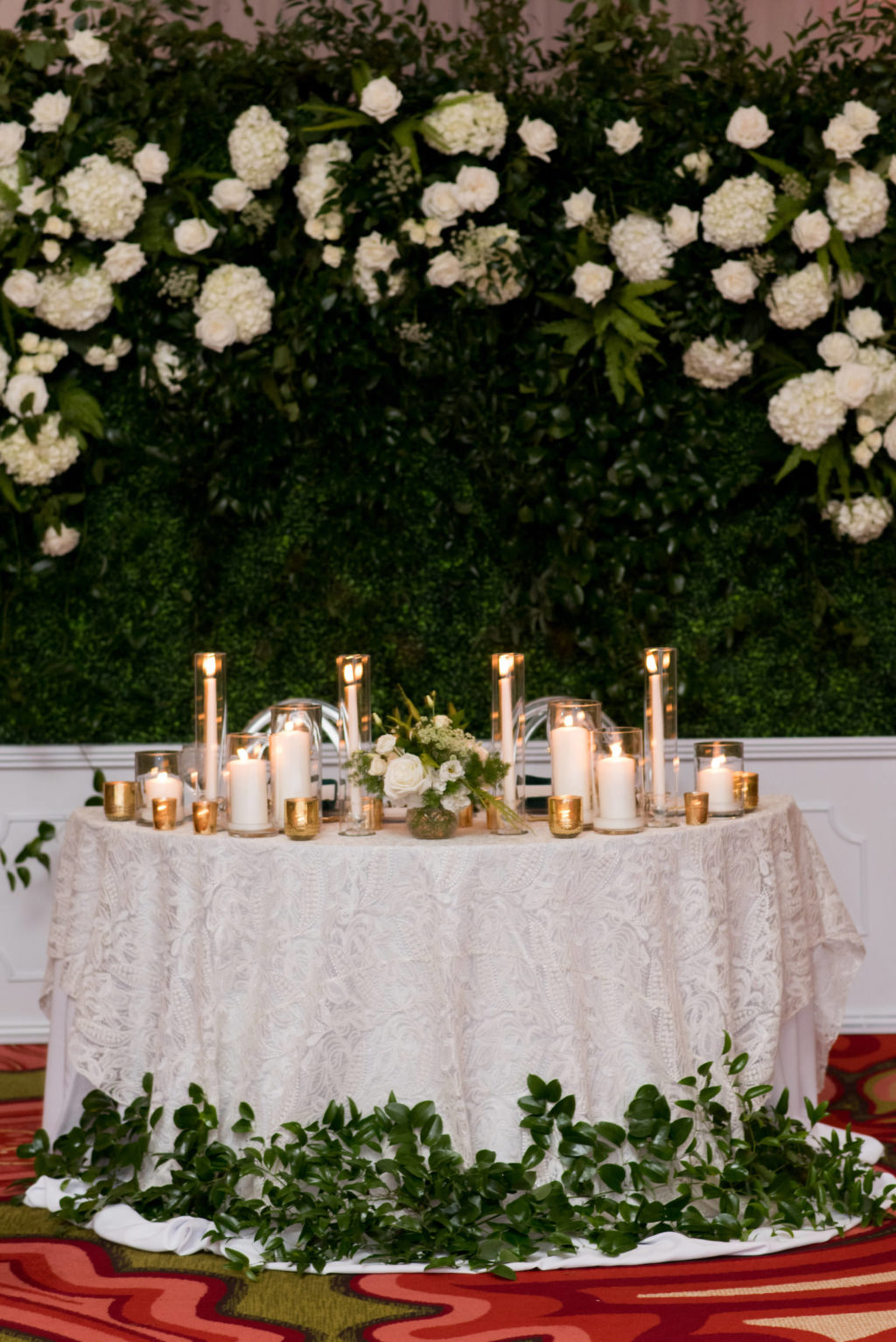 Elegant Wedding Reception Decor, Sweetheart Table with Ivory Lace Linen, Greenery Leaves, Gold and White Candles, Greenery Backdrop with White Hydrangeas and Roses | Tampa Bay Wedding Planner Parties A'la Carte | St. Pete Wedding Venue The Vinoy | Wedding Rentals A Chair Affair | Wedding Florist Bruce Wayne Florals