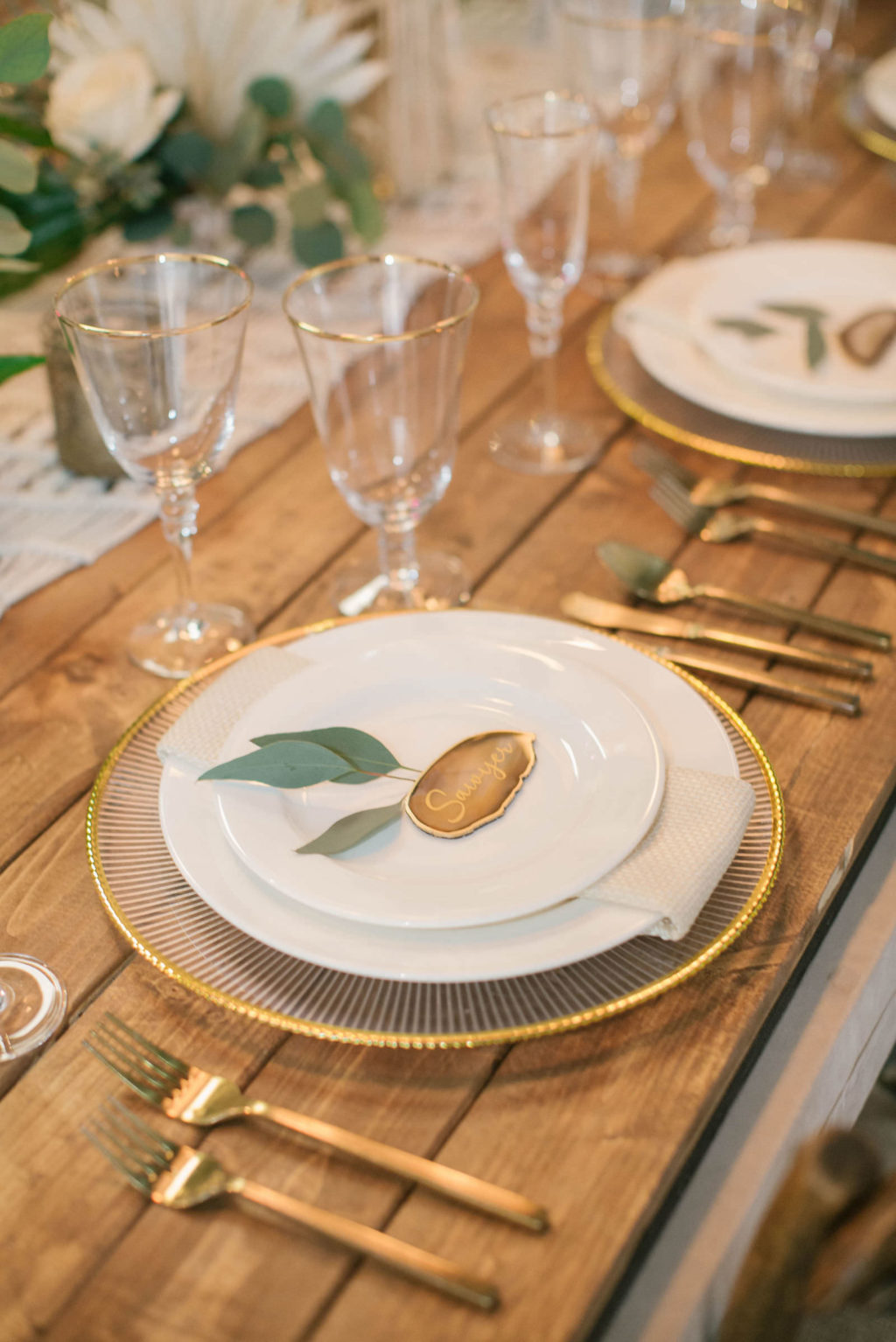 Boho Modern Gold and White Charger with Eucalyptus Greenery Name Card and Golf Flatware on Wooden Feasting Table | Reception Table Decor Ideas | Styled With Love at St. Pete Beach Wedding Venue Bellwether Beach Resort