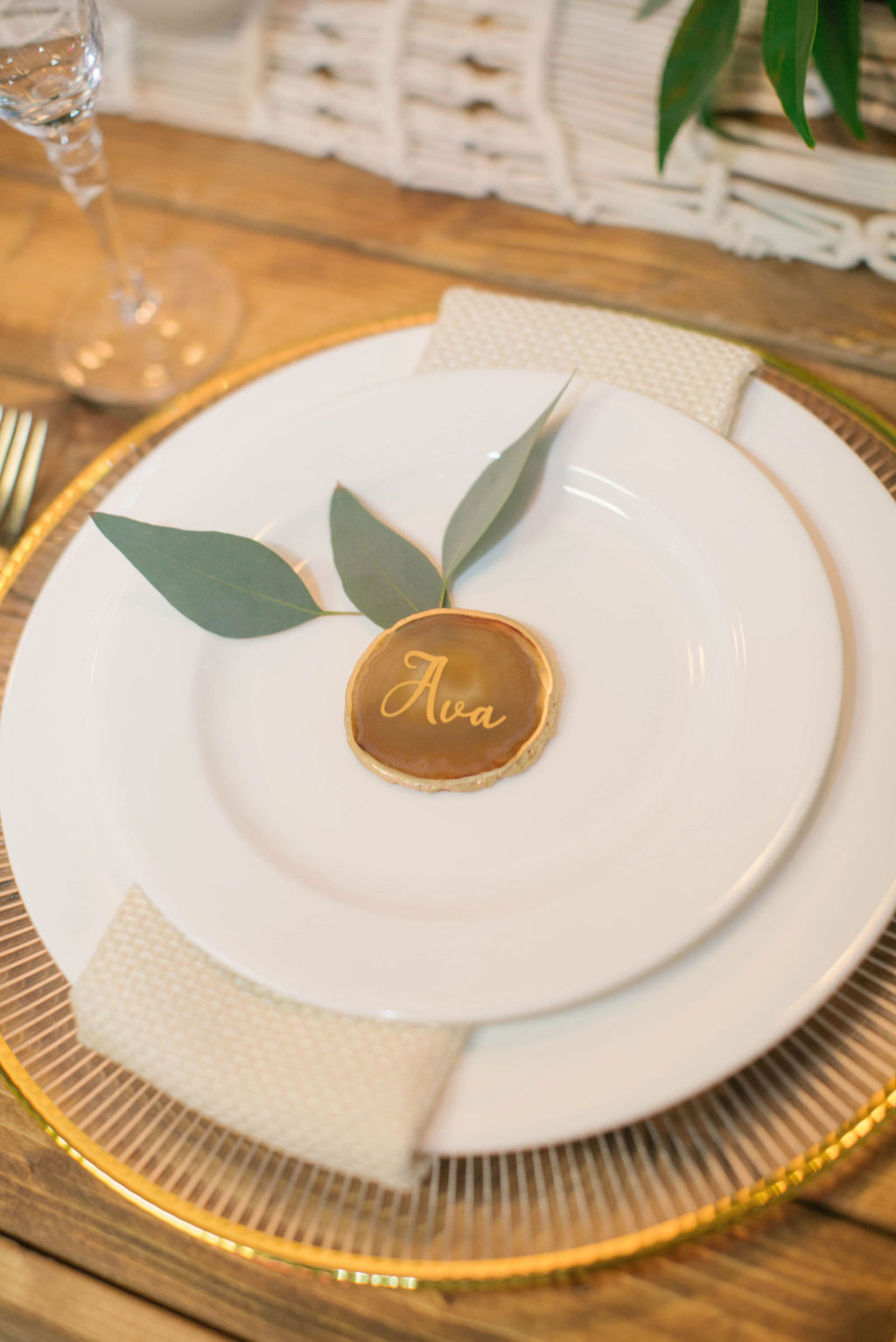 Boho Modern Gold and White Charger with Eucalyptus Greenery Name Card and Golf Flatware on Wooden Feasting Table | Reception Table Decor Ideas | Styled With Love at St. Pete Beach Wedding Venue Bellwether Beach Resort