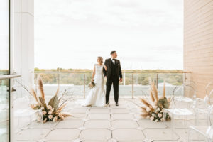 Organic Boho Modern White and Brown Rooftop Wedding Ceremony Flowers with Peach Roses, Gold Leaves, Feathers, and Ghost Chairs | Tampa Bay Wedding Florist Monarch Events | Planner and Designer UNIQUE Weddings + Events | Venue Aloft/Element Midtown | Photographer and Videographer Bonnie Newman Creative | Rentals A Chair Affair