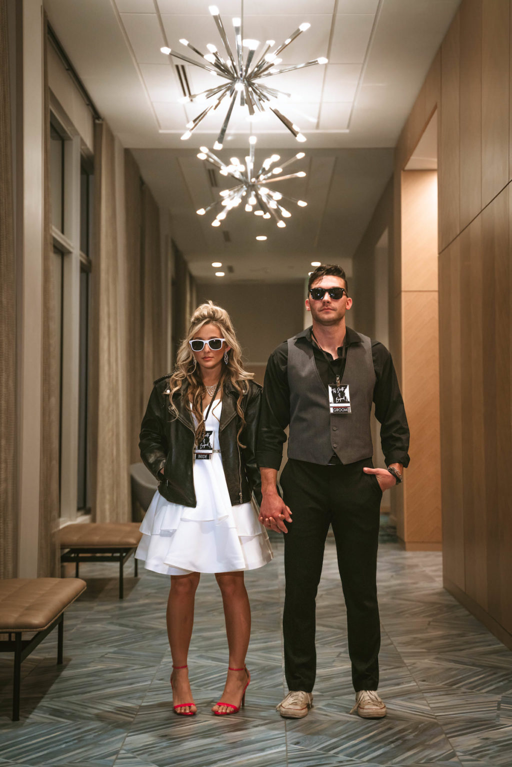 Urban and Edgy Bride in Short Wedding Dress with Black Leather Jacket and Red Shoes, Groom in Black Dress Pants and Shirt with Gray Vest and Sunglasses | Tampa Bay Wedding Photographer Bonnie Newman Creative | Wedding Hair and Makeup Adore Bridal Service | Wedding Dress Truly Forever Bridal | Aloft/ Element Midtown Tampa