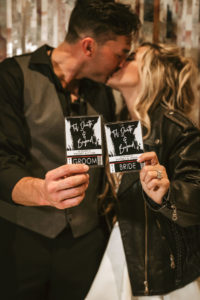 Urban and Edgy Bride in Black Leather Jacket and Short Wedding Dress with Groom in Black Dress Shirt and Pants and Gray Vest Holding VIP Black Backstage Concert Pass Style Wedding Invitations | Tampa Wedding Planner and Designer UNIQUE Weddings and Events | Wedding Photographer Bonnie Newman Creative