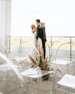 Organic Boho Modern White and Brown Rooftop Wedding Ceremony Flowers with Peach Roses, Gold Leaves, Feathers, and Ghost Chairs | Tampa Bay Wedding Florist Monarch Events | Planner and Designer UNIQUE Weddings + Events | Venue Aloft/Element Midtown | Photographer and Videographer Bonnie Newman Creative | Rentals A Chair Affair