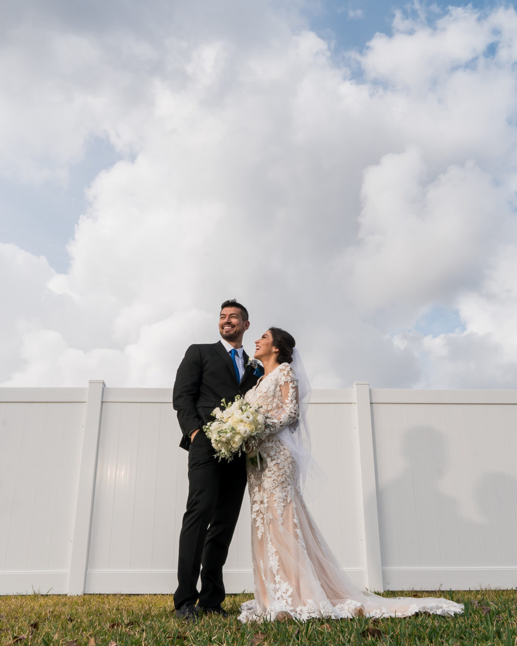 Tampa Bride in Romantic Lace and Illusion Long Sleeve Wedding Dress Holding White Floral Bouquet with Groom