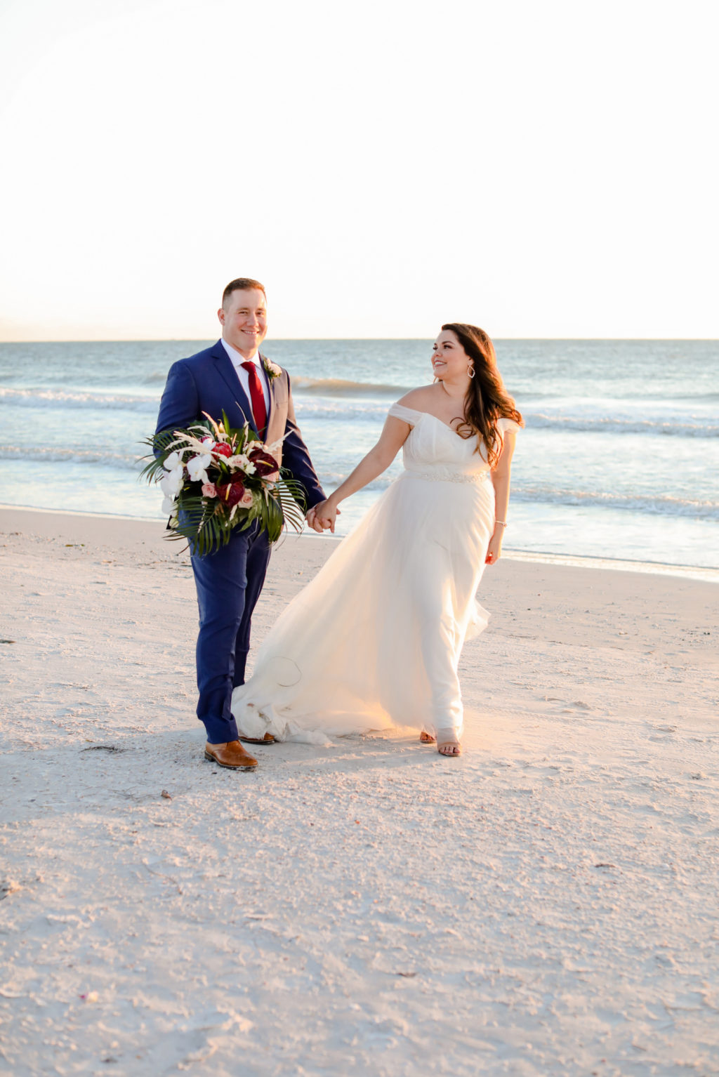 Florida Bride in Boho Off the Shoulder Tulle and Chantilly Lace Wedding Dress with Groom in Blue Suit Holding Bride's Tropical Floral Bouquet | Tampa Bay Wedding Photographer Lifelong Photography Studio | St. Pete Beach Wedding Venue Postcard Inn | Wedding Florist Iza's Flowers