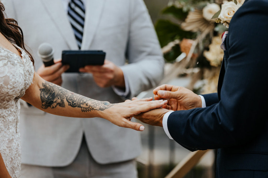 Bride and Groom Exchanging Rings during Boho St. Pete Wedding Ceremony | Bride with Sleeve Tattoo