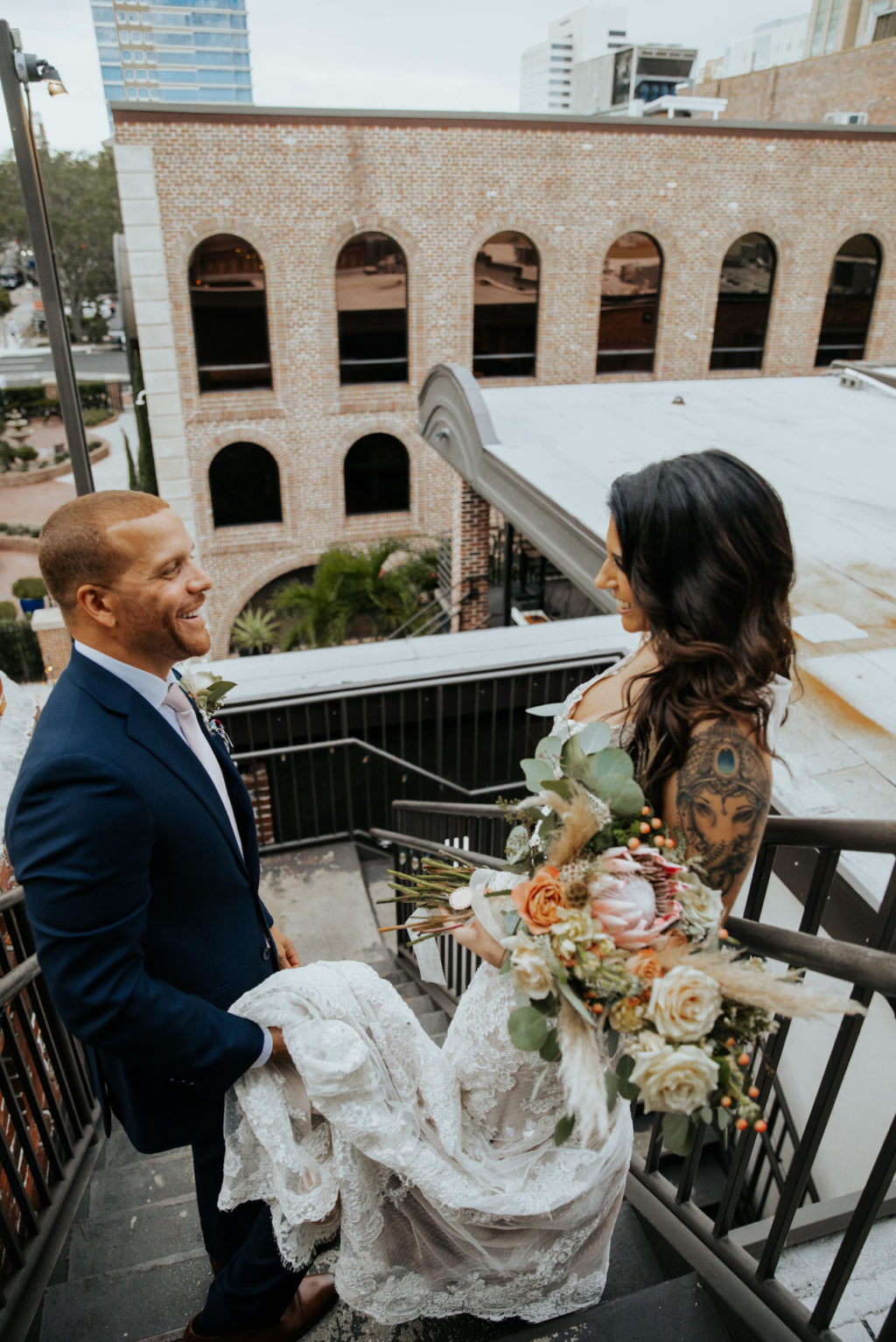 Bride and Groom Outdoor Portrait at Downtown St. Pete Florida Wedding | Boho Wedding Bouquet with white and Copper Roses, Pampas Grass, Eucalyptus Greenery and Protea | Groom Wearing Classic Navy Blue Suit Tux