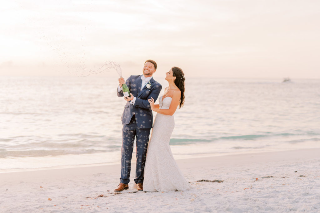 Sarasota Fun Bride and Groom Popping Bottle of Champagne on Beach During Sunset | Tampa Bay Wedding Photographer Kera Photography