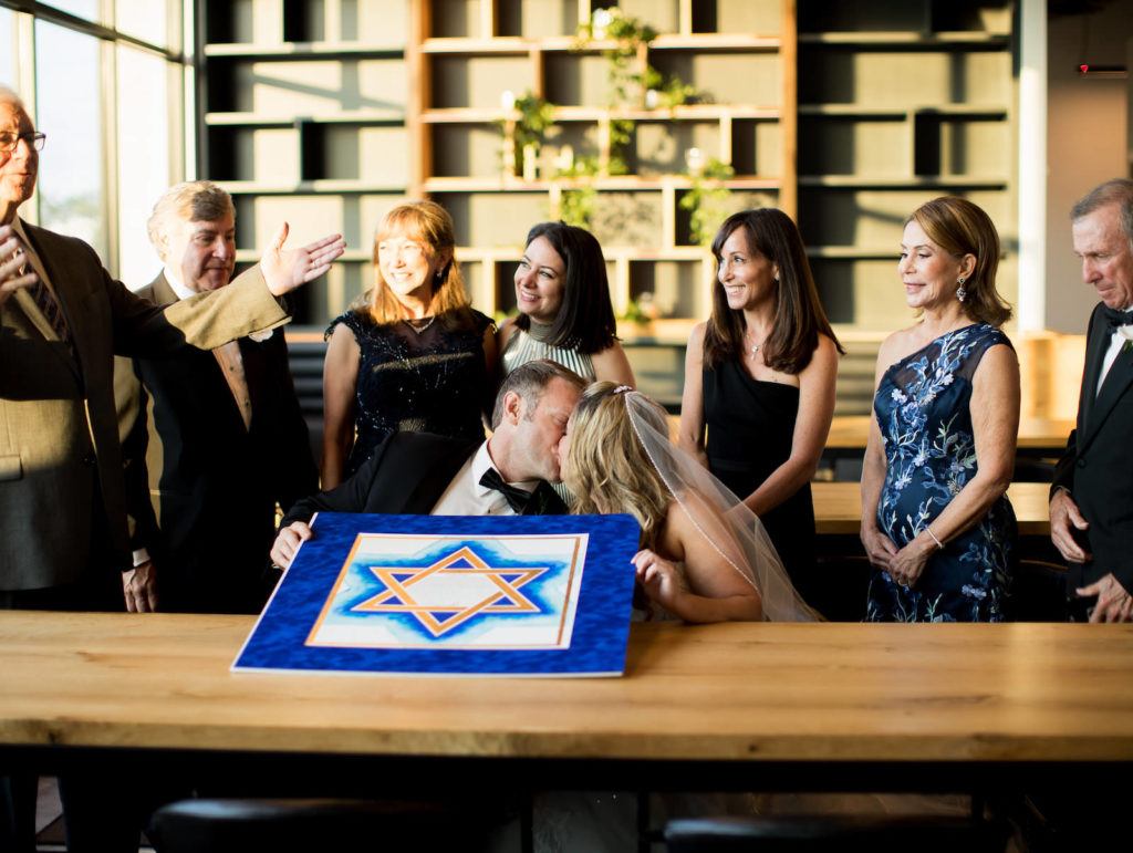 Classic Bride and Groom Kissing Holding Blue and White Jewish Wedding Ketubah Star of David Print with Family | Tampa Bay Wedding Venue Hyde House