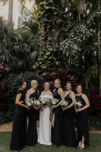 Classic Florida Bridal Party at Sunken Gardens in Downtown St. Petersburg, Brides Wearing Mix, and Match Long Black BHLDN Bridesmaid Dresses, Holding Minimalist White Floral Bouquets with Greenery | Tampa Bay Wedding Hair and Makeup Artist Femme Akoi Beauty Studios