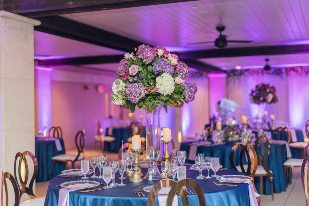 Beach Wedding Reception Decor, Tables with Silk Blue Tablecloths, Purple Linen Napkins, Tall Clear Vase with Purple and Ivory Hydrangeas, Pink Roses Floral Centerpiece | Tampa Bay Wedding Photographer Kera Photography