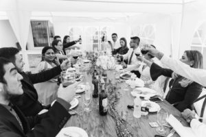Private Residence Wedding Reception in Tent, Guests Cheering at Long Wooden Feasting Table | Tampa Bay Wedding Planner Eventfull Weddings