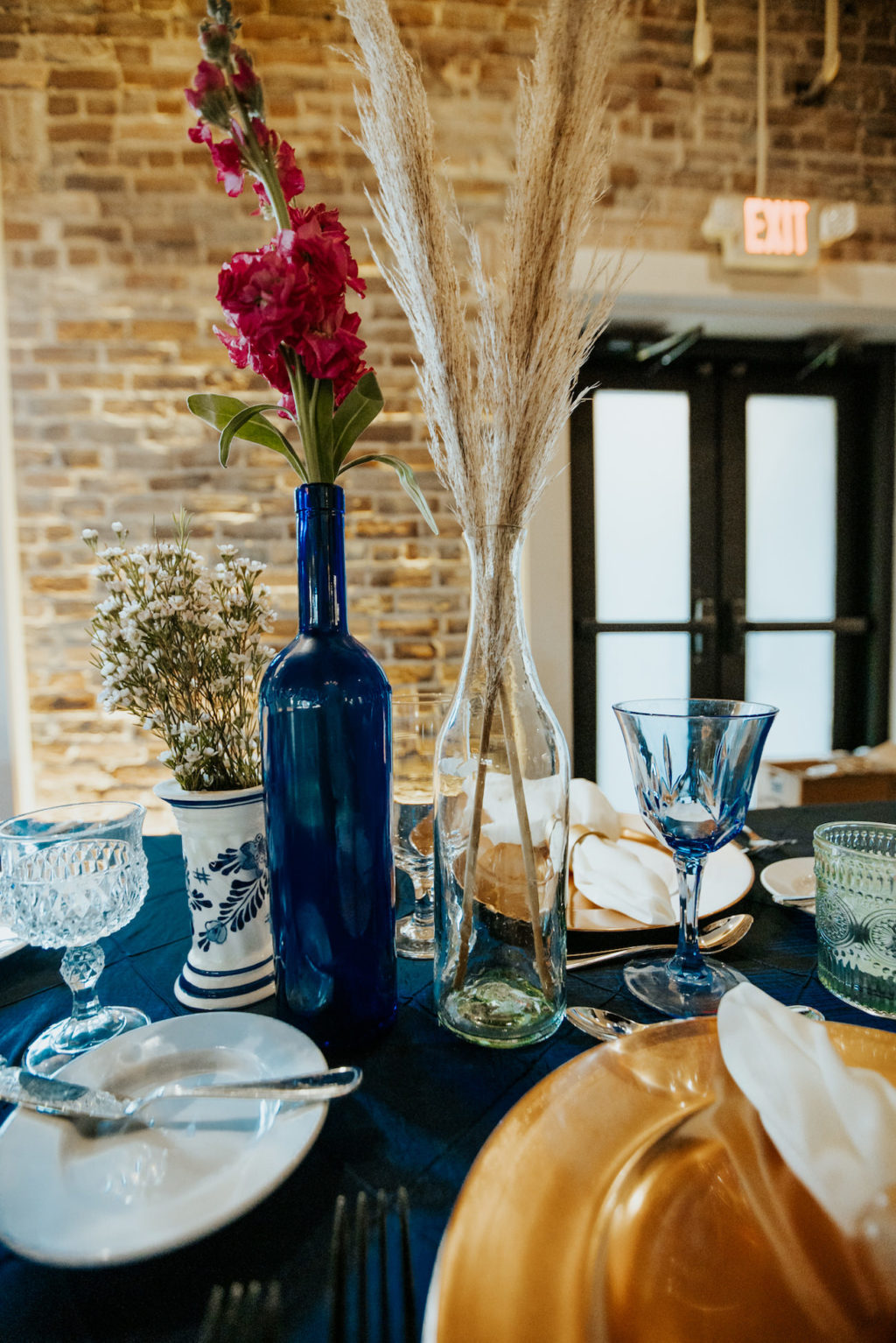 Boho Wedding Reception at Downtown St. Pete Venue Red Mesa Events | Navy Blue Reception Tables with Copper Gold Charger Plates and White Napkins with DIY Thrift Store Mismatched Bud Vase Centerpieces