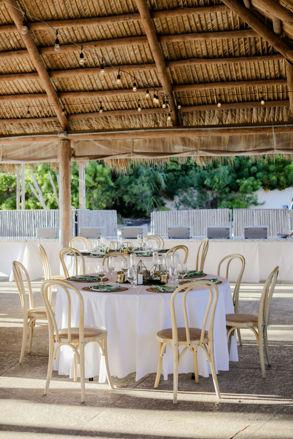 Tropical Wedding Reception Decor, Round Tables with White Linen Tablecloths, Wooden Bamboo Chairs, Hanging String Lights| | St. Pete Beach Wedding Venue Postcard Inn on the Beach | Tampa Bay Wedding Photographer Lifelong Photography Studio