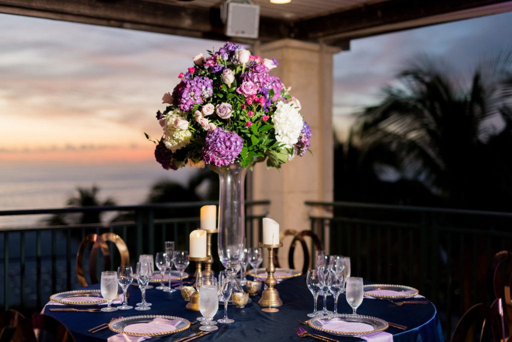 Beach Wedding Reception Decor, Tables with Silk Blue Tablecloths, Purple Linen Napkins, Tall Clear Vase with Purple and Ivory Hydrangeas, Pink Roses Floral Centerpiece | Tampa Bay Wedding Photographer Kera Photography | Beach Waterfront Wedding Venue Ritz Carlton Sarasota