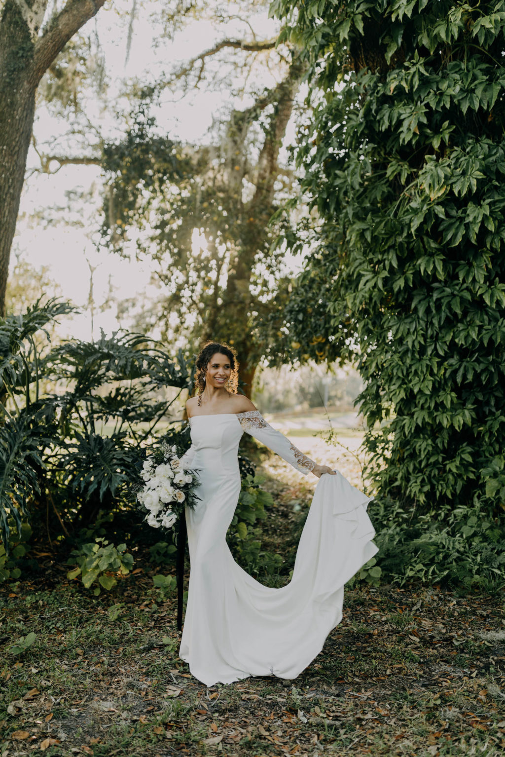 Outdoor Bridal Portrait | Florida Winter Wedding Bouquet with White Peony Garden Roses, Ranunculus, and Pine Greenery | Off the Shoulder Lace Sleeve Sheath Wedding Gown Bridal Dress | Amber McWhorter Photography