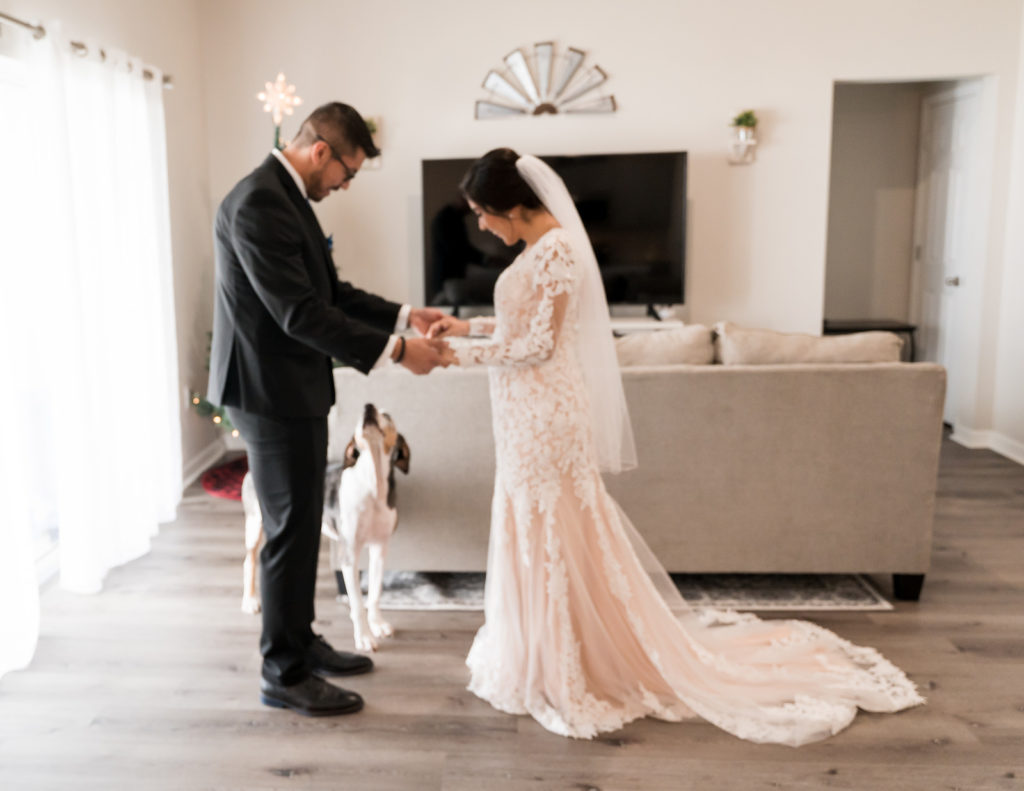 Tampa Bride in Romantic Lace and Illusion Wedding Dress with Nude Lining Long Sleeves Holding Hands with Groom During First Look and Dog