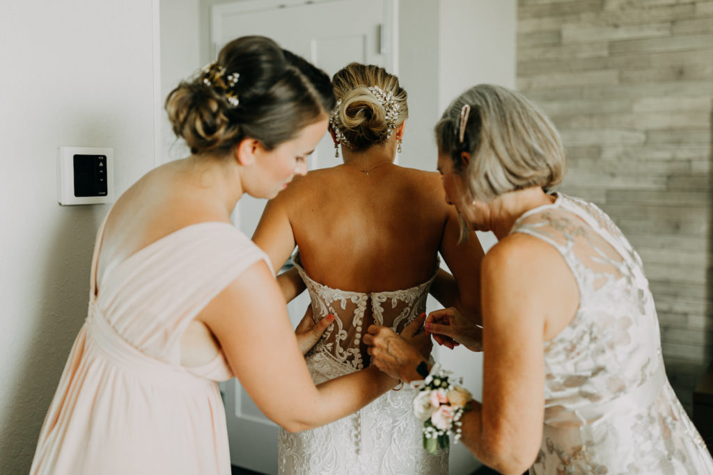 Florida Bride Getting Wedding Ready Putting on Lace and Illusion Strapless Wedding Dress with Mom and Bridesmaids | Tampa Bay Wedding Photographer Amber McWhorter Photography